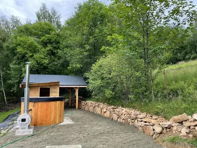 a wooden building with a stone wall next to a house at Modrzewiowe Domki w Koszarawie in Koszarawa