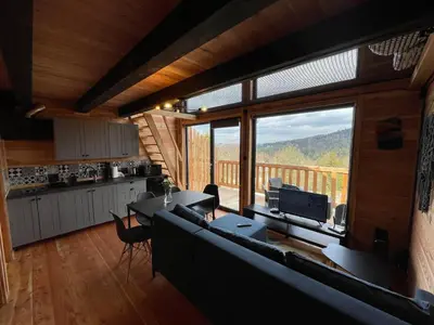 a living room with a couch and a large window at Modrzewiowe Domki w Koszarawie in Koszarawa