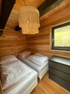 two beds in a log cabin with a chandelier at Modrzewiowe Domki w Koszarawie in Koszarawa