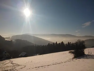 a snow covered field with the sun in the sky at Agroturystyka Millerówka in Kamionka Mała