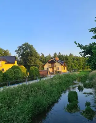 a river in front of a house and a house at MARMI Noclegi in Golczowice