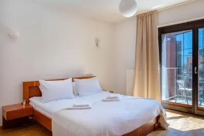 a bedroom with a large white bed with a large window at Wygodny Apartament Przy Dworcu in Kraków