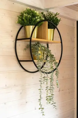 a black circle hanging on a wall with plants at Staymoovers - Tinyhouse Zator in Zator