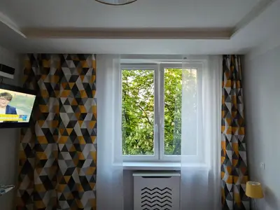a window in a room with curtains and a television at Komfortowo i cicho - Apartament in Kraków