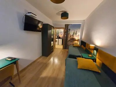 a living room with a blue couch and a television at Komfortowo i cicho - Apartament in Kraków