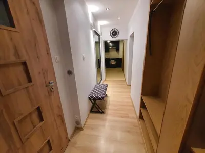 a hallway with a wooden door and a chair at Komfortowo i cicho - Apartament in Kraków