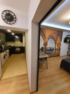 a kitchen and a living room with a clock on the wall at Komfortowo i cicho - Apartament in Kraków