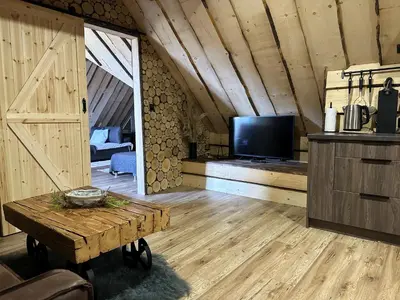 a living room with a tv and a wooden floor at Loft Na Stodole z jaskinią SPA - Osada Jaworzyny in Zawadka