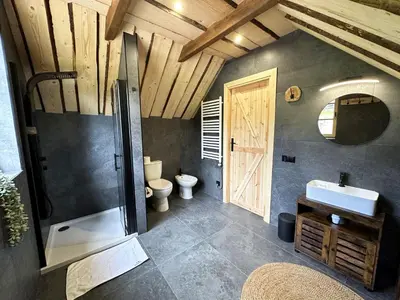 a bathroom with a toilet and a sink and a door at Loft Na Stodole z jaskinią SPA - Osada Jaworzyny in Zawadka