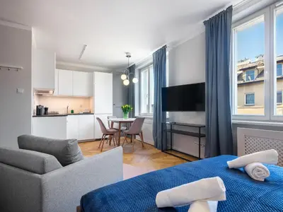 a living room with a bed and a kitchen at Tyzenhauz Apartments Rakowicka Street in Kraków
