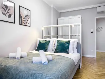 a bedroom with a bed with white and green pillows at Tyzenhauz Apartments Rakowicka Street in Kraków