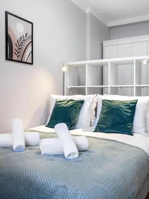 a bedroom with a large bed with white and green pillows at Tyzenhauz Apartments Rakowicka Street in Kraków
