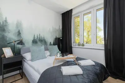 a bedroom with a bed and a table and windows at Modern Apartment Grzegórzeckie Roundabout Cracow by Noclegi Renters in Kraków