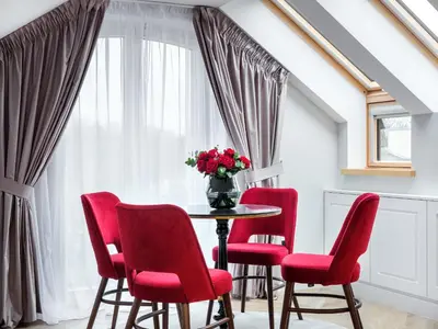 a dining room with red chairs and a table with a vase of flowers at Golden Queen Deluxe Jacuzzi Apartments - Old Town in Kraków