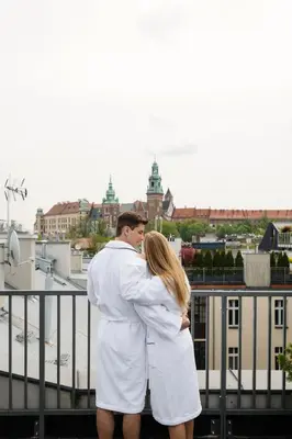 a man and a woman dressed in white standing on a balcony at Golden Queen Deluxe Jacuzzi Apartments - Old Town in Kraków