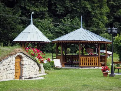 two gazebos in a park with a bench and flowers at Pokoje Gościnne Młyn Bosaka in Ojców