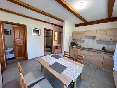 a dining room with a table and a kitchen at Pokoje Gościnne Młyn Bosaka in Ojców