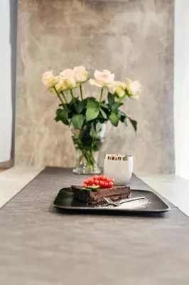 a black plate with a cake and a vase of roses at Golden Queen Apartments Old Town in Kraków