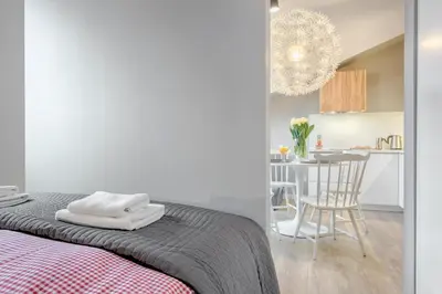a bedroom with a bed and a kitchen with a table at Tyzenhauz Apartments Arianska Street in Kraków