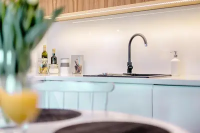 a kitchen with a sink and a counter with wine bottles at Tyzenhauz Apartments Arianska Street in Kraków