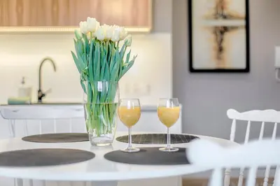 two glasses of wine and a vase of flowers on a table at Tyzenhauz Apartments Arianska Street in Kraków