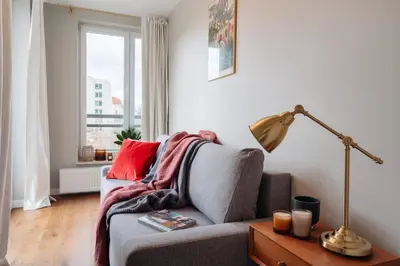 a living room with a couch and a lamp and a window at Tyzenhauz Apartments Arianska Street in Kraków