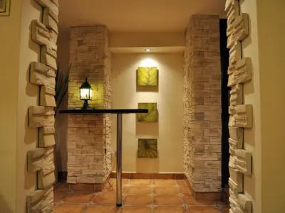 a hallway with stone walls and a table with a lamp at Najlepsze Miejsce - pokoje i apartamenty w Krakowie in Kraków