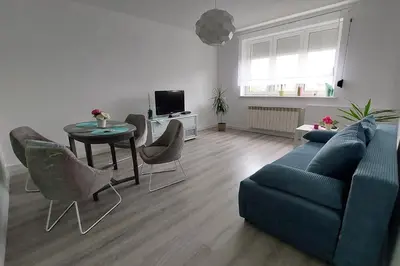 a living room with a blue couch and a table and chairs at Apartament Emmi in Imielin