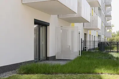 a building with glass doors and grass on the side at Family Apartment with Parking & Terrace by Noclegi Renters in Kraków