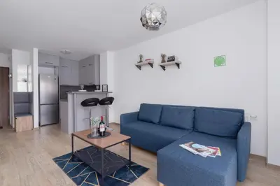 a living room with a blue couch and a table at Family Apartment with Parking & Terrace by Noclegi Renters in Kraków