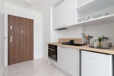 a kitchen with white counters and a wooden door at Elegant Pet-Friendly Studio in Krakow by Noclegi Renters in Kraków