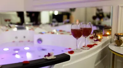 two glasses of wine sitting on a bath tub at Vistula Boulevards Jacuzzi Apartment in Kraków