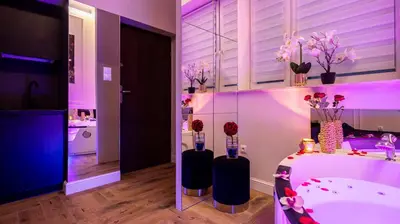 a bathroom with a tub with vases with flowers in it at Vistula Boulevards Jacuzzi Apartment in Kraków