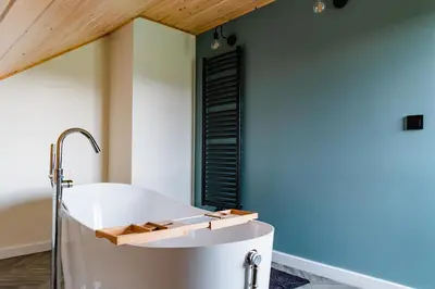 a bath tub in a bathroom with a blue wall at NOVMI - Domki letniskowe