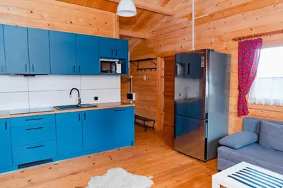 a kitchen with blue cabinets and a refrigerator at NOVMI - Domki letniskowe