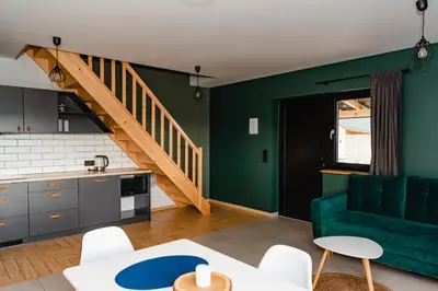a living room with a green couch and a staircase at NOVMI - Domki letniskowe