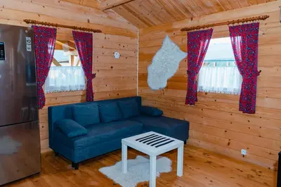 a living room with a blue couch in a log cabin at NOVMI - Domki letniskowe