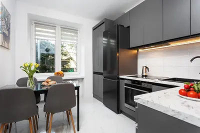 a kitchen with black appliances and a table and chairs at Cosy Corner - Kraków, Krowodrza - by Upstairs in Kraków
