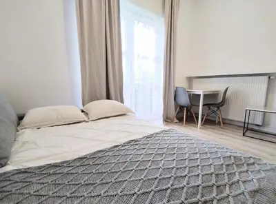 a bedroom with a bed and a table and a window at White Studio in Wieliczka