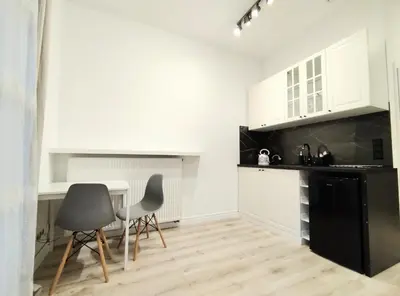 a kitchen with white cabinets and a table and chairs at White Studio in Wieliczka