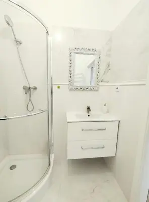 a white bathroom with a shower and a sink at White Studio in Wieliczka