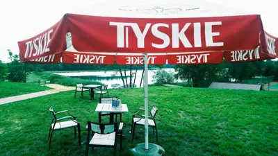 a table and chairs under an umbrella in the grass at Gościniec nad Zalewem Sosina in Jaworzno