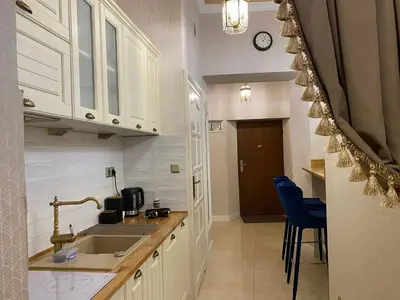 a kitchen with white cabinets and a sink and blue chairs at Radiance Residence in Kraków