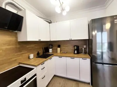 a kitchen with white cabinets and a stainless steel refrigerator at Sołtysa Dytmara 3 by Homeprime in Kraków