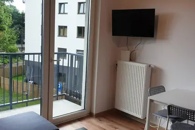 a room with a balcony with a television and a table at Wygodny apartament niedaleko centrum by Krakow Home in Kraków