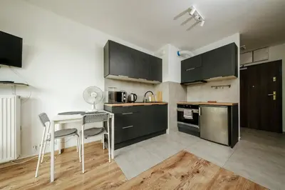 a kitchen with black cabinets and a table and chairs at Wygodny apartament niedaleko centrum by Krakow Home in Kraków