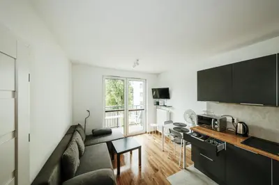 a living room with a couch and a kitchen at Wygodny apartament niedaleko centrum by Krakow Home in Kraków