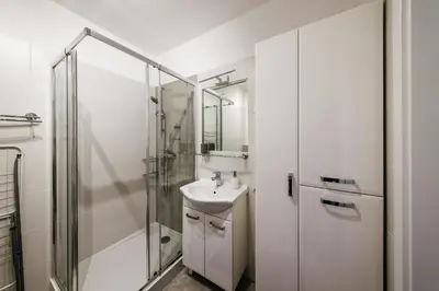 a white bathroom with a sink and a shower at Wygodny apartament niedaleko centrum by Krakow Home in Kraków
