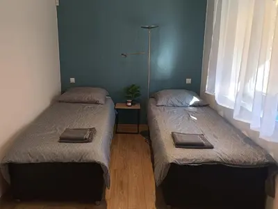 two twin beds in a room with a green wall at Dom nad Stryszawką z SAUNĄ - domek wypoczynkowy in Stryszawa