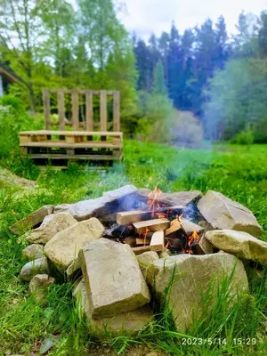 a fire pit with rocks and a bench in a field at Dom nad Stryszawką z SAUNĄ - domek wypoczynkowy in Stryszawa